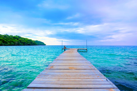 The wooden bridge stretches into the sea.With  Mountain clouds and sky.の写真素材