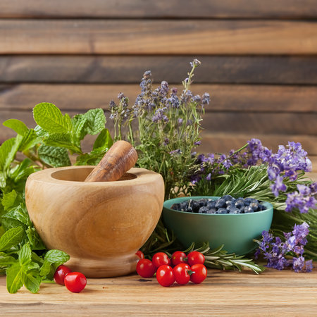 Herbs, berries and flowers with mortar, on wooden table backgroundの素材