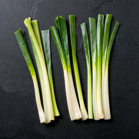 Minimal flat lay looking leeks view during slice progress over blackの素材