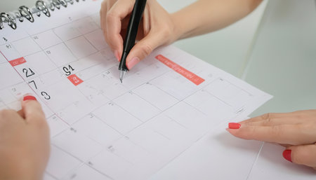 Woman hand carrying calendar and pointing on it by penの素材