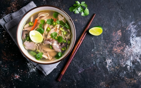 Plate of Vietnamese pho bo soup on a dark background, top viewの素材