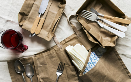 Paper bag with a picnic set plate, fork, glass, napkins. Caring for the environmentの素材