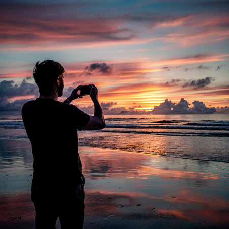 Man taking a picture of the sunset on the beachの素材