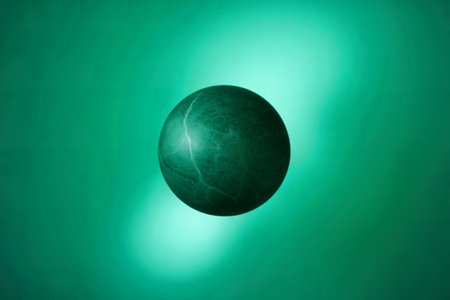 A perfectly round sphere of green marble is shown against a teal backdrop. The marble's veining is visible, adding texture and depth.の素材