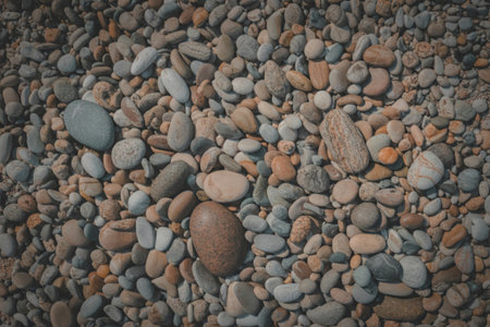 A textured overhead view of a diverse collection of smooth rounded beach pebbles