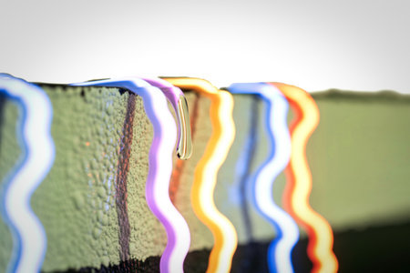 Close-up view of multicolored neon lights with a wavy pattern, one dripping a viscous substance onto...