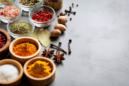 A collection of various spices in small bowls and scattered across a light gray surface, creating a vibrant culinary display.の写真素材
