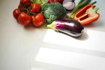 A vibrant collection of fresh vegetables including tomatoes, broccoli, eggplant, bell pepper, and...