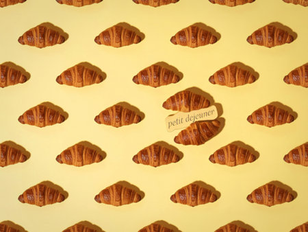 A seamless pattern of freshly baked golden croissants is disrupted by a single pair of croissants pulled slightly apart, revealing their flaky layers.の写真素材