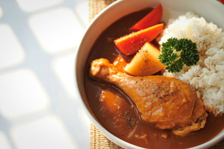 A close-up shot of a hearty chicken curry served with fluffy white rice. A comforting and flavorful meal.の写真素材