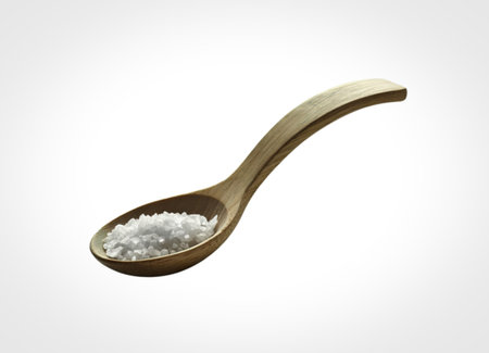 A close-up shot of a wooden spoon holding a small pile of white granular material, isolated on a white background.の写真素材