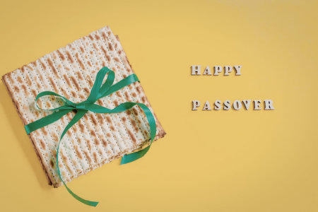A wrapped gift with a green ribbon on a yellow background with Happy Passover text