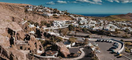 A panoramic view of a coastal town with white buildings and winding roads, situated on a hillside...