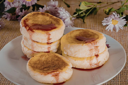 A delicious plate of pancakes with strawberry syrup drizzled on top, placed on a table with flowers...