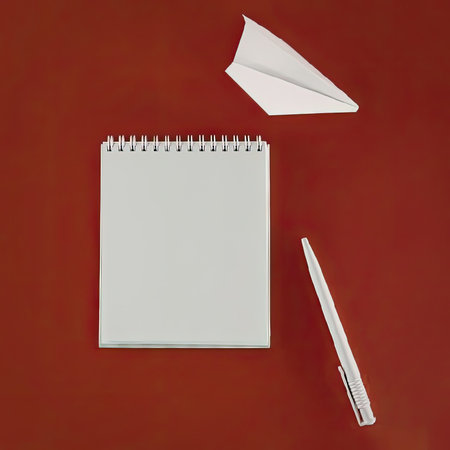 A spiral notebook, a pen, and a paper airplane on a red background.