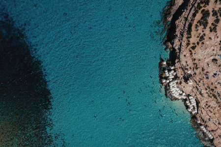 An aerial view of a coastal landscape featuring a vibrant blue body of water and a rugged shoreline...