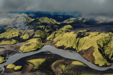 An aerial view of a serene landscape featuring green mountains and a winding river under a cloudy...