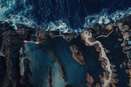 An aerial view of a rugged coastline with waves crashing against the rocks, creating a mesmerizing...