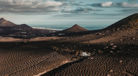 An aerial view of a rural landscape featuring mountains, fields, and a cloudy sky.