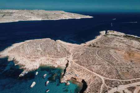 Aerial view of rocky coastline with boats in clear blue water