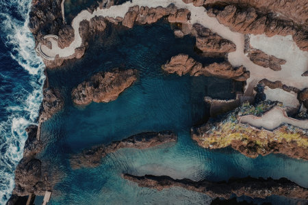 The image captures a breathtaking aerial view of a rugged coastline, featuring rocky shores, sandy...