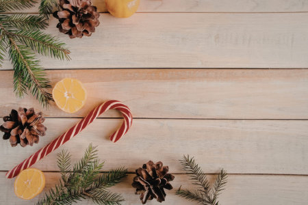 A festive arrangement of Christmas decorations on a wooden table, featuring a candy cane, pinecones,...
