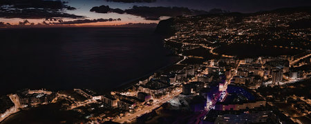 Cityscape at dusk with vibrant nightlife and coastal views