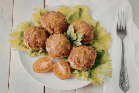 The image shows a plate of five meatballs placed on a bed of fresh lettuce, accompanied by sliced...