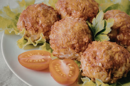 The image features a plate of meatballs garnished with lettuce and tomato slices, showcasing a...