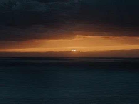 A serene and dramatic scene of a sunset over the ocean, with dark clouds looming above and a calm...