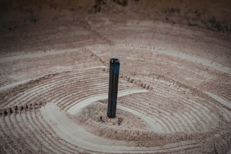 A drill bit is positioned in the center of a circular pattern on a surface, with concentric rings...