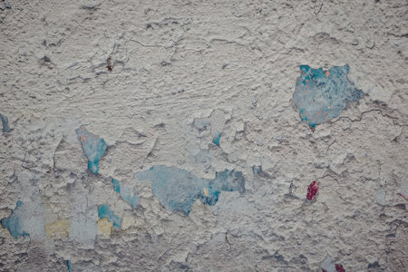The image depicts a weathered concrete surface with remnants of faded paint in various colors,...