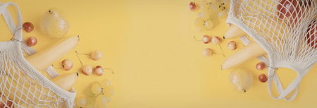 A vibrant yellow background with white mesh bags spilling out various fruits like apples, bananas,...