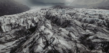 The image depicts a vast, rugged landscape dominated by a glacier with intricate patterns of snow...