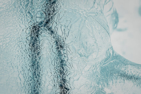 a close-up view of a frozen windowpane with ice crystals and water dropletsの写真素材