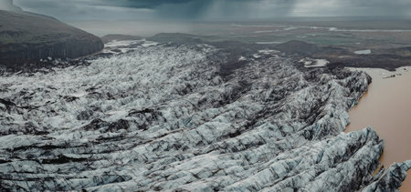 A stunning aerial view of a glacier meeting a river, showcasing the contrast between the icy blue...