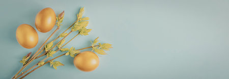 Three golden eggs placed on green stems with leaves against a light blue background