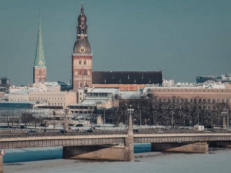 A serene cityscape featuring a bridge over a river, with historic towers and buildings in the...
