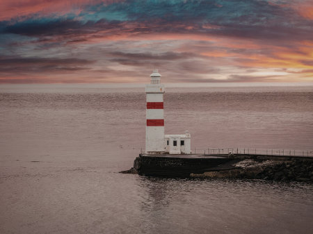 Lighthouse standing tall on a rocky jetty at serene dusk