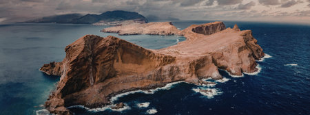 The image depicts a rugged island with rocky terrain surrounded by deep blue waters, showcasing a...