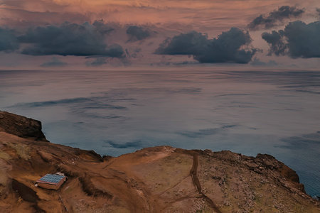 A breathtaking landscape at dusk, featuring a rugged terrain and a cloudy sky with hues of orange...