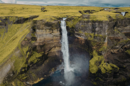 The image captures a breathtaking aerial view of a waterfall cascading into a calm pool, surrounded...