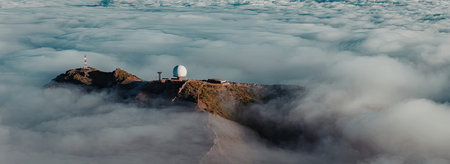 A mountain peak emerges from a sea of clouds, featuring an observatory on its summit.