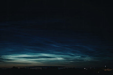 The image captures a serene night sky with glowing clouds and the silhouette of a city in the...