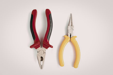 The image shows two types of pliers, one with red and black handles and the other with yellow...