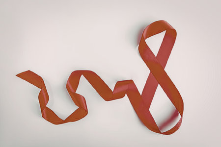 A red ribbon laid out in a wavy pattern on a plain white background