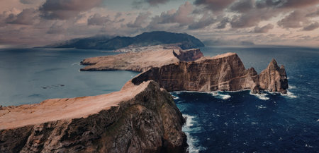 Rugged coastline with rocky outcrops and distant mountains under cloudy sky