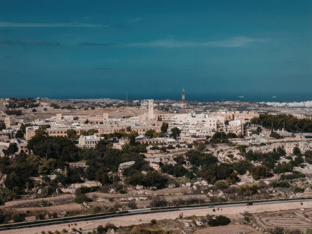 The image depicts a scenic aerial view of a cityscape with numerous buildings and trees under a...