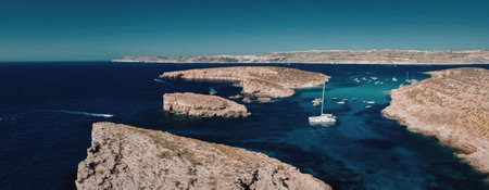 A serene and picturesque scene of a sailboat navigating through the crystal clear waters of an...