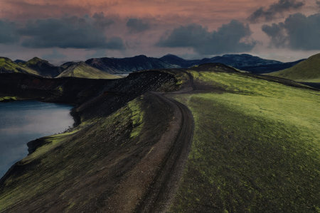 Serene landscape with winding dirt road and tranquil lake